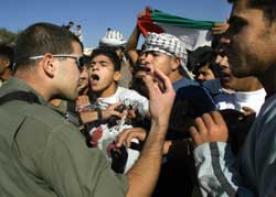 An Israeli border policeman argues with Palestinians demonstrating