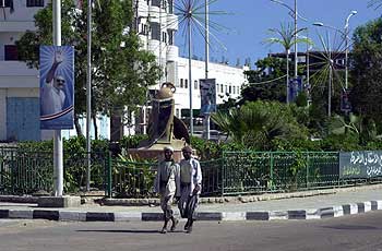 Yemeni men walk down a street adorned with pictures of President Ali Abdullah Saleh