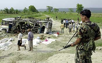 A Nepalese soldier stands guard at the wreckage of a passenger bus